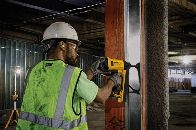 Worker using DEWALT tool, SKUs DGN845D1-QW and DGN845D1, on a metal frame at construction site.